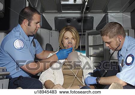 Stock Image - Paramedics taking care of victim in ambulance. Fotosearch