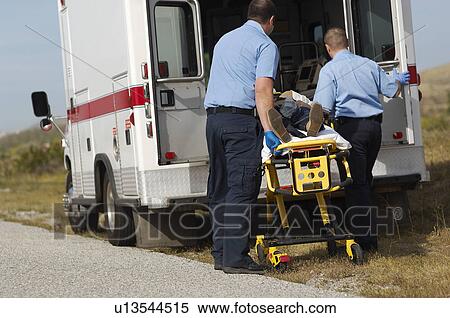 Stock Photography - Paramedics transporting victim on stretcher. Fotosearch
