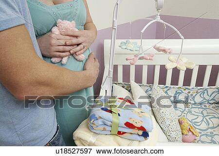 Stock Photo - Parents standing by cradle, mid section. Fotosearch
