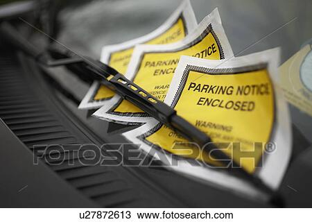 Stock Image - Parking tickets under windshield wiper, close-up. Fotosearch