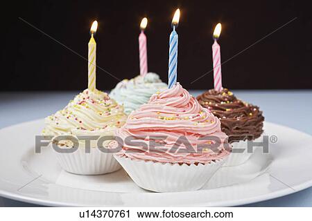 Stock Image - Pastel cupcakes with birthday candles on plate. Fotosearch
