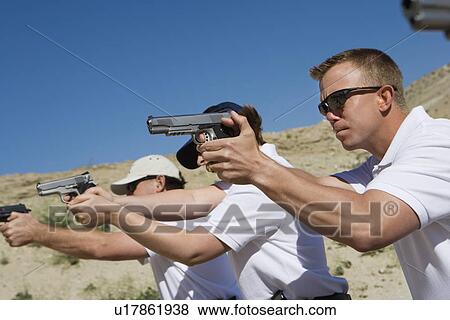 Stock Photo - People aiming hand guns at firing range. Fotosearch