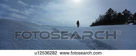 Stock Image - Person walking in snow. Fotosearch