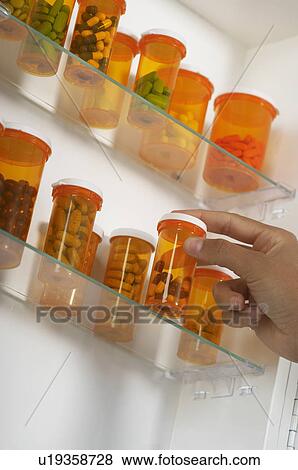 Stock Photo - Person's hand taking pill bottle from shelf. Fotosearch