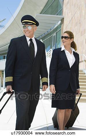 Pilot and flight attendant walking outside building View Large Photo Image Picture - Pilot and flight attendant walking outside building. Fotosearch
