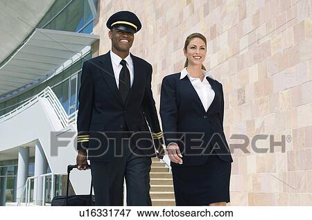 Pilot and flight attendant walking outside building View Large Photo Image Stock Photo - Pilot and flight attendant walking outside building. Fotosearch
