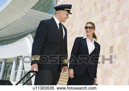 Pilot and flight attendant walking outside building, low angle view View Large Photo Image Stock Photography - Pilot and flight attendant walking outside building, low angle view. Fotosearch