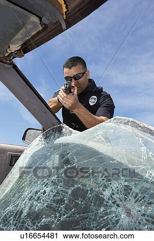 Police officer aiming gun through broken car windshield View Large Photo Image Stock Image - Police officer aiming gun through broken car windshield. Fotosearch