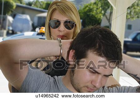 Stock Image - Police Officer Arresting Young Man. Fotosearch