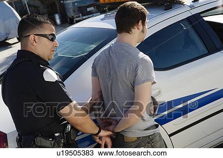 Stock Image - Police Officer Arresting Young Man. Fotosearch