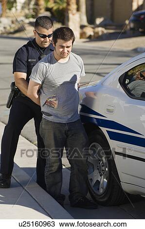 Stock Image - Police Officer Arresting Young Man. Fotosearch
