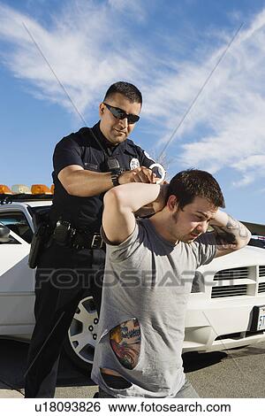 Stock Photograph - Police Officer Arresting Young Man. Fotosearch