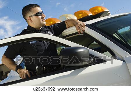 Stock Image - Police Officer Leaning on Patrol Car. Fotosearch
