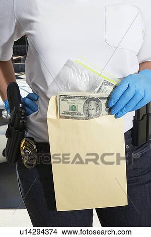 Picture - Police Officer Putting Money in Evidence Envelope. Fotosearch
