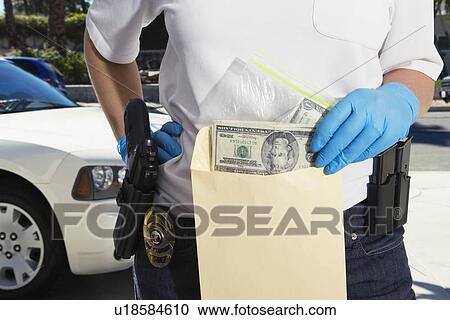 Stock Image - Police Officer Putting Money in Evidence Envelope. Fotosearch