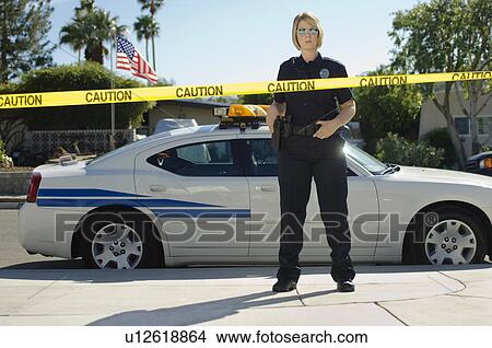 Picture - Police Officer Standing Behind Police Tape. Fotosearch