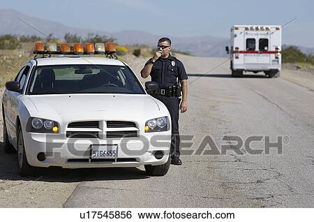 Stock Photograph - Police officer using CB radio on desert road. Fotosearch