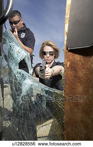 Police officers aiming guns through broken car windshield View Large Photo Image Stock Photograph - Police officers aiming guns through broken car windshield. Fotosearch