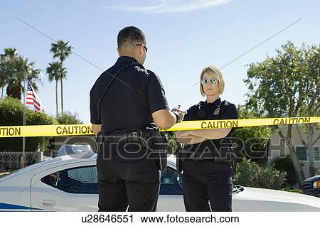 Stock Image - Police Officers Separated by Police Tape. Fotosearch
