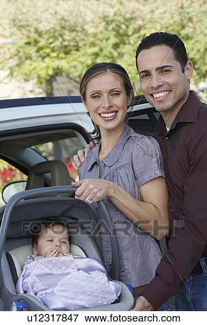 Portrait of couple with baby (1-6 months) in carrier by car View Large Photo Image Stock Photo - Portrait of couple with baby (1-6 months) in carrier by car. Fotosearch
