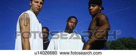Stock Image - Portrait of four men against blue sky. Fotosearch