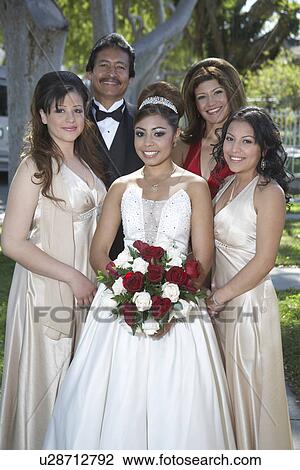 Stock Image - Portrait of girl (13-15) with parents and friends in garden at Quinceanera. Fotosearch