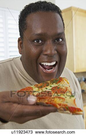 Stock Image - Portrait of man eating pizza. Fotosearch