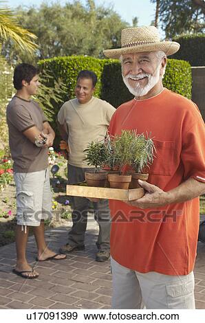 Stock Photo - Portrait of man holding flowers in garden. Fotosearch