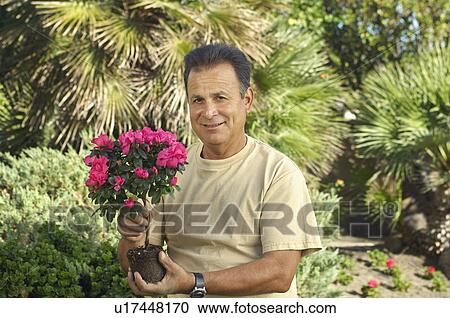 Stock Image - Portrait of man with flowers in garden. Fotosearch