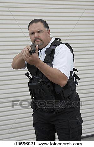 Portrait of security guard in bulletproof vest holding gun View Large Photo Image Stock Image - Portrait of security guard in bulletproof vest holding gun. Fotosearch