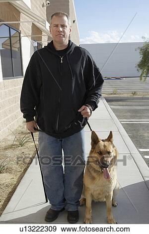 Stock Photo - Portrait of security guard with dog, outdoors. Fotosearch