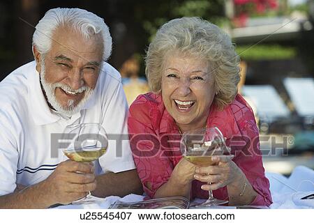 Portrait of senior couple relaxing in garden with wine and laughing View Large Photo Image Stock Photo - Portrait of senior couple relaxing in garden with wine and laughing. Fotosearch