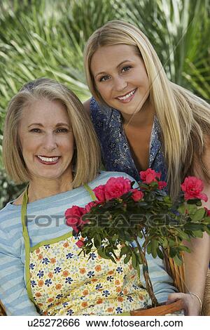 Stock Photograph - Portrait of two women with flowers in garden. Fotosearch