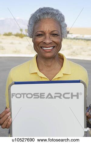 Stock Image - Portrait of woman holding sign outdoors. Fotosearch