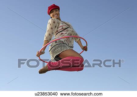 Stock Image - Portrait of woman jumping with Hula Hoop. Fotosearch