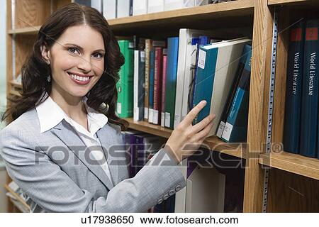 Portrait of woman reaching for book from bookshelf View Large Photo Image Stock Image - Portrait of woman reaching for book from bookshelf. Fotosearch