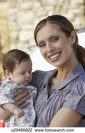 Stock Image - Portrait of woman with baby (1-6 months), close-up. Fotosearch