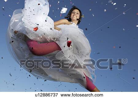 Portrait of young woman in wedding dress jumping View Large Photo Image Stock Photo - Portrait of young woman in wedding dress jumping. Fotosearch
