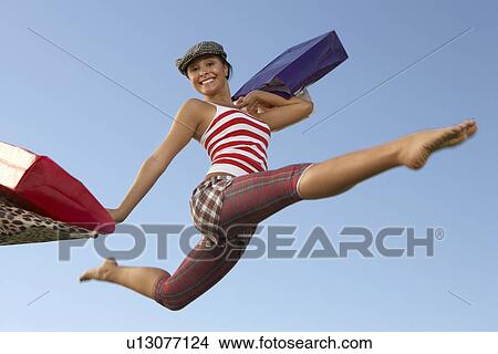 Portrait of young woman jumping with shopping bags View Large Photo Image Picture - Portrait of young woman jumping with shopping bags. Fotosearch