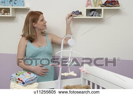 Pregnant woman arranging things in baby room View Large Photo Image Stock Photography - Pregnant woman arranging things in baby room. Fotosearch