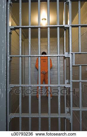 Stock Photograph - Prisoner standing in prison cell. Fotosearch
