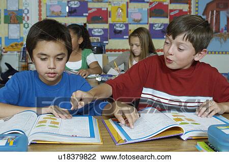 Stock Image - Pupils in classroom reading their textbooks. Fotosearch