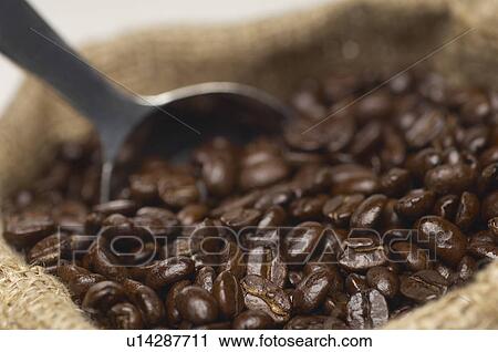 Stock Image - Sack of coffee beans with spoon, close-up. Fotosearch