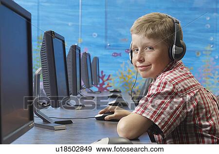 School boy wearing headphones in computer room, portrait View Large Photo Image Stock Photo - School boy wearing headphones in computer room, portrait. Fotosearch