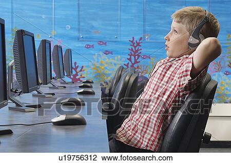 School boy wearing headphones, relaxing in computer room View Large Photo Image Stock Image - School boy wearing headphones, relaxing in computer room. Fotosearch