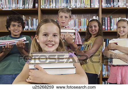 Stock Photo - School children holding books in library, portrait. Fotosearch