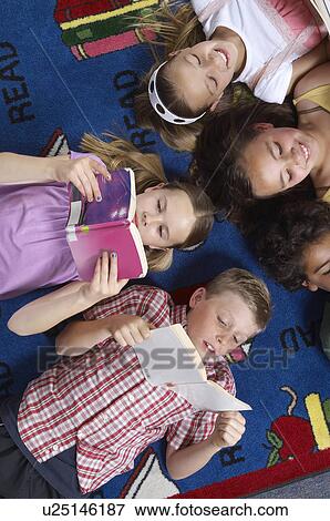 School children reading books on floor in library View Large Photo Image Stock Photo - School children reading books on floor in library. Fotosearch