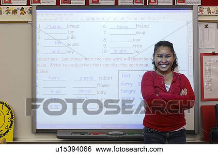 Stock Photograph - Schoolgirl standing in classroom, projection screen behind her. Fotosearch