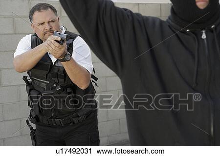 Stock Image - Security guard aiming gun at thief. Fotosearch