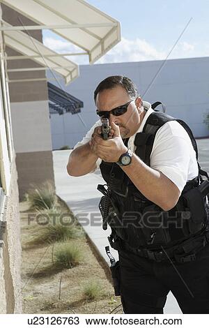 Stock Image - Security guard aiming with gun outdoors. Fotosearch